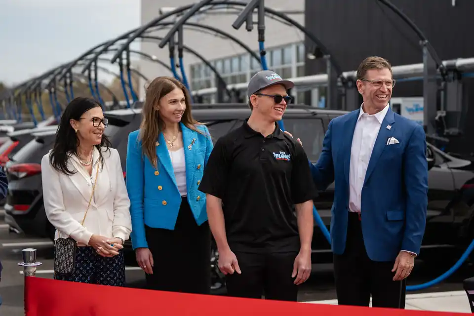 The family who own and operate The Flow Express Car Wash, standing with a team member outside the Naperville wash